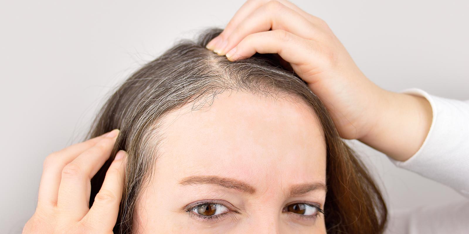 Is your hair color making you look older? (woman examining her hair)