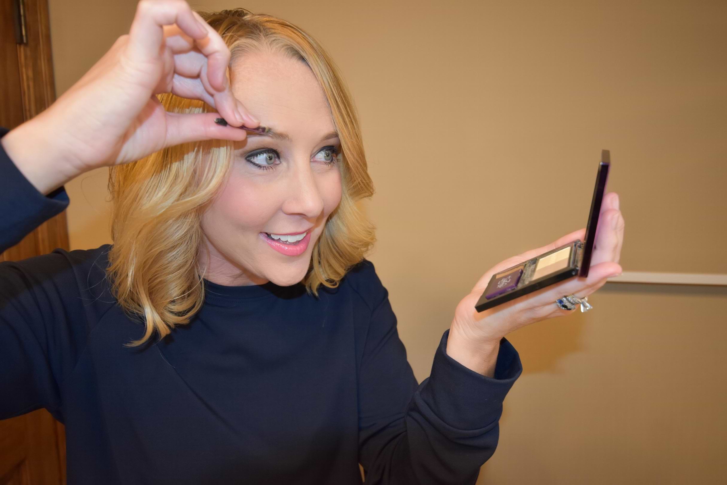 Blonde haired woman filling in her eyebrows with Madison Reed The Great Cover Up